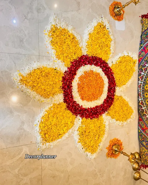 A top-down view of a large flower rangoli I designed for an Annaprashan ceremony. The vibrant colors of marigold, rose, and chrysanthemum petals create a stunning pattern on the floor.
