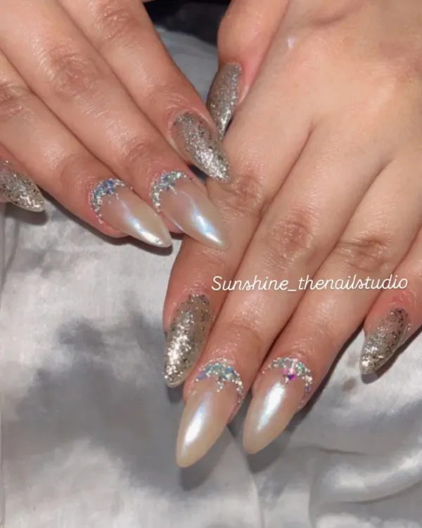Shine bright with this combination of gold glitter and pearl chrome nails. This stiletto set is accented with a half-moon of rhinestones for extra sparkle.