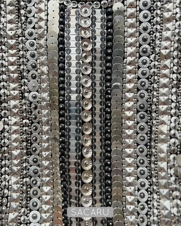 A detailed view of the meticulous hand embroidery on a brocade halter neck piece, showcasing rows of silver metal sequins and beads.