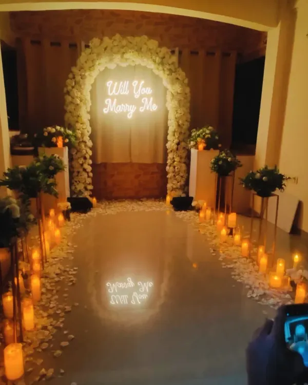 The perfect surprise proposal. I created this romantic scene with a pathway of candles, a beautiful white floral arch, and a glowing "Will You Marry Me" sign.