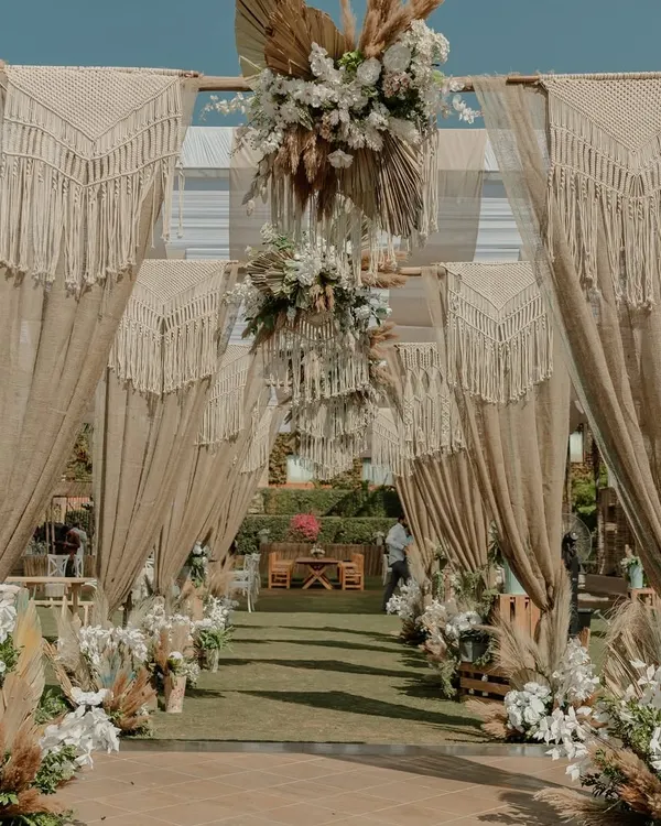 A Tulum-inspired welcome lunch. The couple wanted a neutral-toned, chic, and soulful vibe, so we used macrame curtains, pampas grass, and earthy textures to create this serene and stylish entrance.