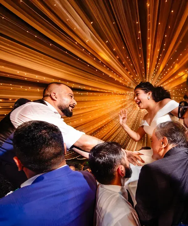 The bride and groom are lifted up by friends and family on the dance floor. The radial lights create a fantastic sense of energy and celebration.