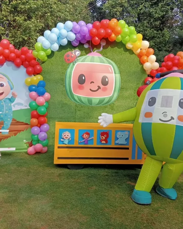 This Cocomelon setup is perfect for an outdoor garden party. It features a large backdrop with the show's characters, a balloon arch in rainbow colors, and even a mascot character for the kids to interact with.