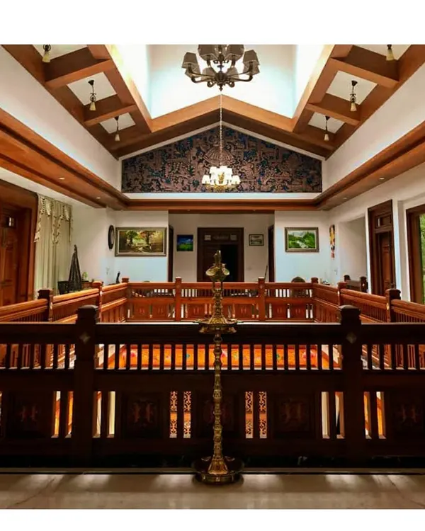 The central courtyard, or 'muttam', is a key feature of this traditional Kerala style house. The intricately carved wooden railings and double-height space with a skylight create a bright and airy core for the home.