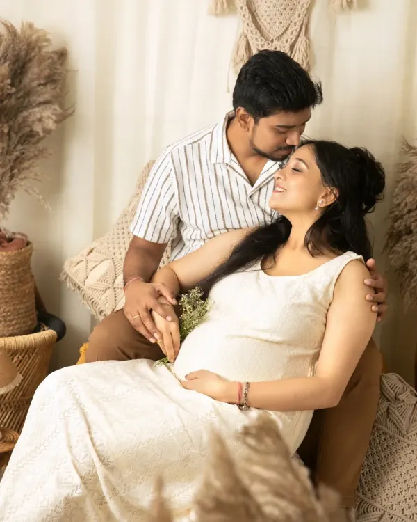 A tender moment from a boho maternity session, where a husband kisses his wife's forehead as they hold hands, both cherishing the anticipation of their new arrival.
