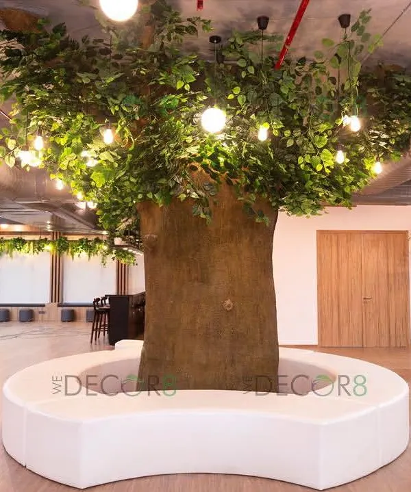 This stunning artificial tree serves as the centerpiece of a large office, creating an immediate connection to nature. We designed it with integrated bench seating to be a functional and inspiring hub for employees to gather, collaborate, or simply take a mindful break.