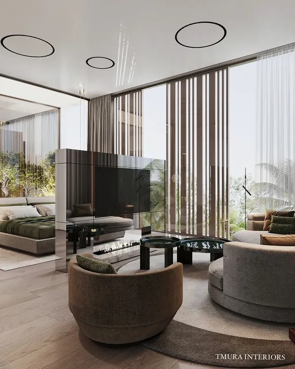 This master suite is designed as a multi-functional retreat, with a distinct seating area for relaxation. The centerpiece is a custom-made, mirrored, rotatable TV unit that elegantly divides the sleeping and lounging zones.