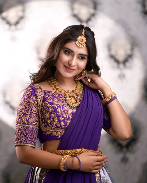 A stunning close-up of our purple half-saree. The blouse features intricate gold embroidery, paired perfectly with traditional gold jewelry, also available for rent.