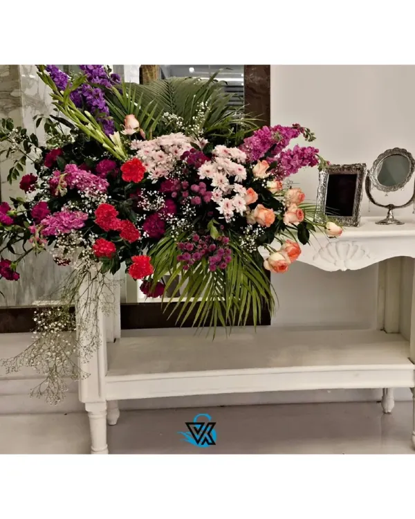 A large, cascading floral arrangement on a console table. We use a mix of flowers and greenery to create arrangements that are full of texture, color, and life.