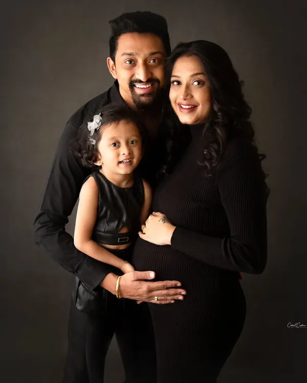 A beautiful family portrait in coordinated black outfits. Big sister is looking so proud and excited to welcome her new sibling.