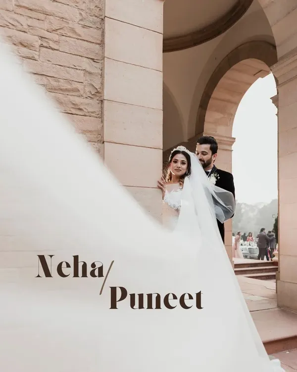 A dramatic portrait of a bride and groom outside a gorgeous Victorian-style church in Delhi. The flowing veil adds a touch of cinematic elegance to their Christian wedding photo.