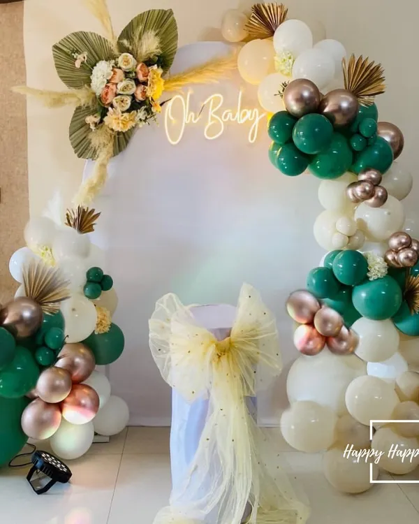 Our modern boho baby shower setup is perfect for a stylish celebration. This design features a lush balloon arch in emerald green, white, and chrome gold, accented with dried pampas grass and a custom "Oh Baby" neon sign to create a stunning focal point.