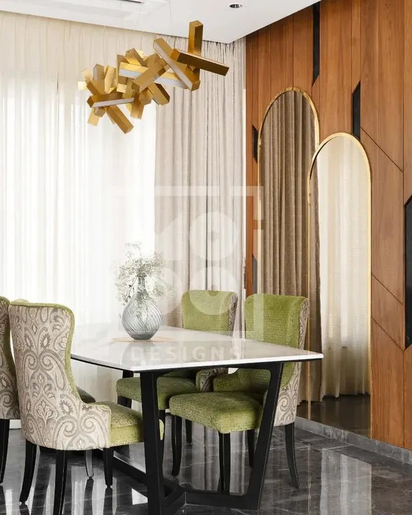 Welcome to our recently handed-over Dadar project. This dining area features plush green chairs, a statement chandelier, and a rich wood-paneled wall, creating a space that is perfect for elegant entertaining.