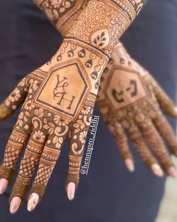 A great way to add personal touches without disrupting the flow of the design. This back-hand henna incorporates the couple's initials and a long-distance relationship symbol in a subtle and stylish way.