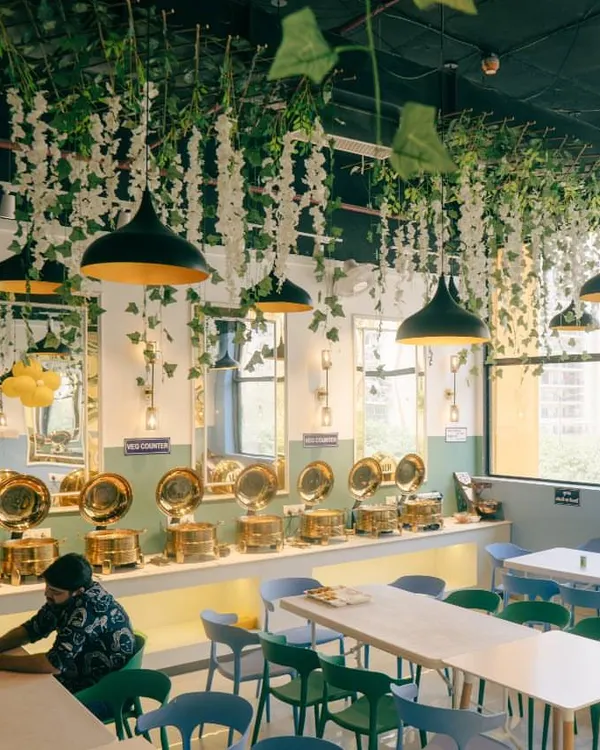 A wide view of my restaurant's interior. I love the hanging greenery and modern light fixtures that create a warm and inviting ambiance for my guests.