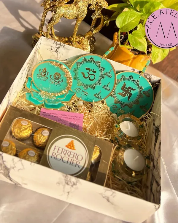 This ready-to-ship Diwali hamper is packed with love and festive essentials. It includes a beautiful resin Lakshmi Ganesh standee, a set of two Shubh Labh hangings, and two t-light holders with real botanicals, making it a complete and thoughtful gift.