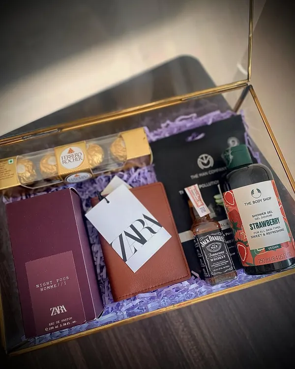 A luxury gift hamper for that special someone. This glass box includes a Zara perfume and wallet, Body Shop shower gel, Ferrero Rocher, a Jack Daniel's miniature, and a Man Company sheet mask.