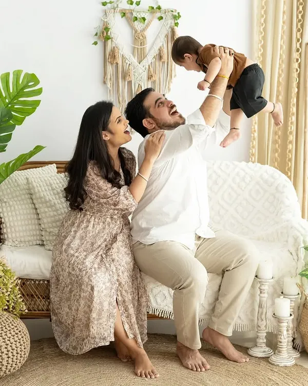 A playful and heartwarming family photo. The father lifting his baby high in the air captures a moment of pure, unfiltered happiness that makes for a wonderful memory.