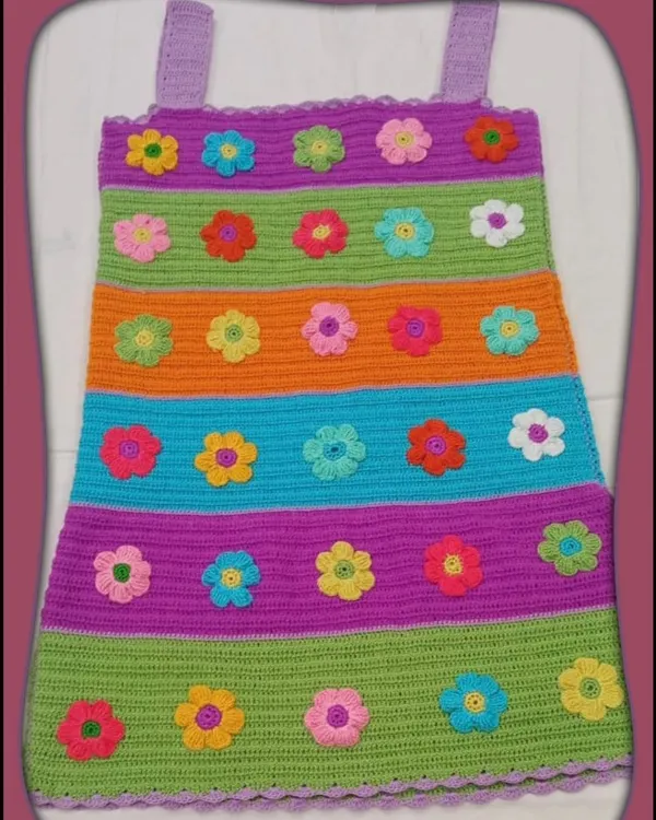 This vibrant, striped crochet dress is one of my favorite custom projects. It's covered in dozens of tiny, hand-stitched flowers, making it a playful and eye-catching piece for any special occasion.