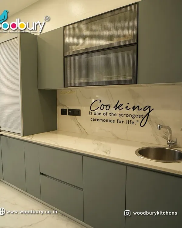 This is a look at one of our recent custom modular kitchens. We focused on a clean, modern design with handle-less cabinets, a durable countertop, and a marble-finish backsplash that's easy to clean. The quote on the wall is a small touch that makes the space feel personal.