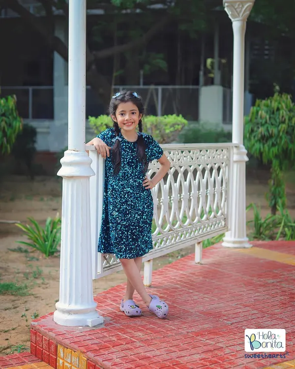 This confident portrait was taken outdoors for a brand collaboration, showcasing a stylish blue dress against the natural backdrop of a park.