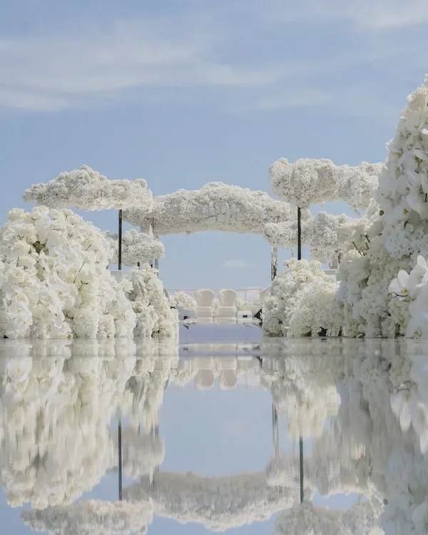 I designed this ethereal all-white wedding ceremony in Cannes, featuring floating floral clouds and a mirrored aisle that reflected the sky, creating a pathway that felt like walking on air towards the sea.