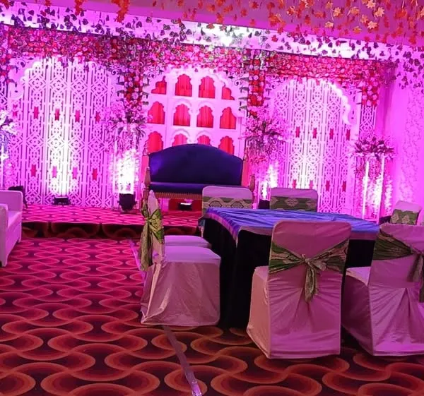 A full view of our main event hall, transformed with custom purple uplighting and elegant stage decor. This versatile space is fully adaptable for large corporate galas, award ceremonies, or grand wedding receptions, demonstrating our expertise in atmospheric lighting and spatial design.