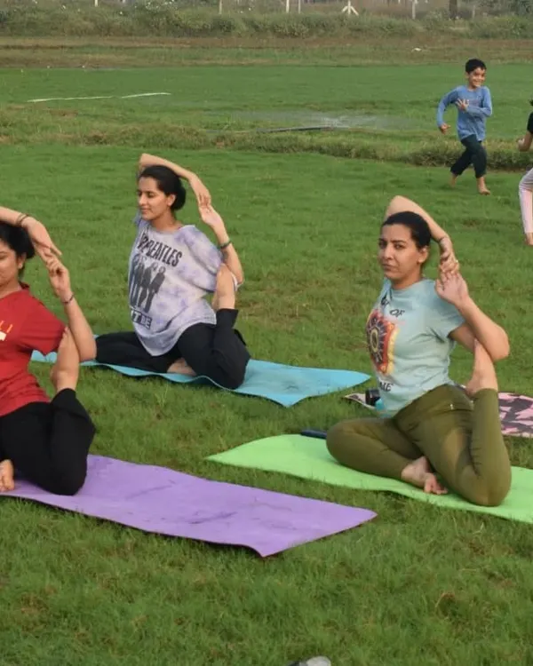 A group of students practicing Mermaid pose in the park. Doing yoga outdoors helps us connect with nature and feel more grounded.