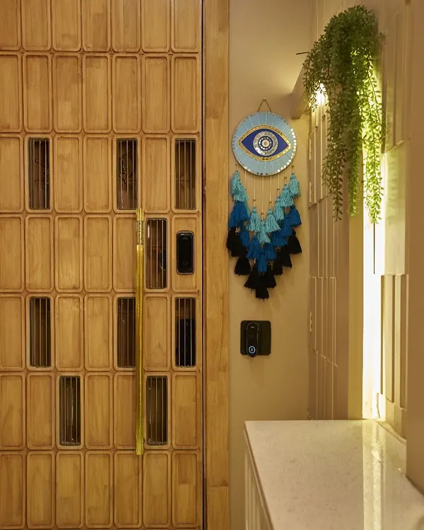 The entrance to your home should make a statement. This custom wooden door with intricate paneling, paired with an evil eye charm, creates a warm and personal welcome.