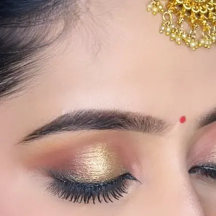 A close-up of a classic golden shimmer eye makeup. This look is perfect for traditional wear, adding a touch of glamour that beautifully catches the light.