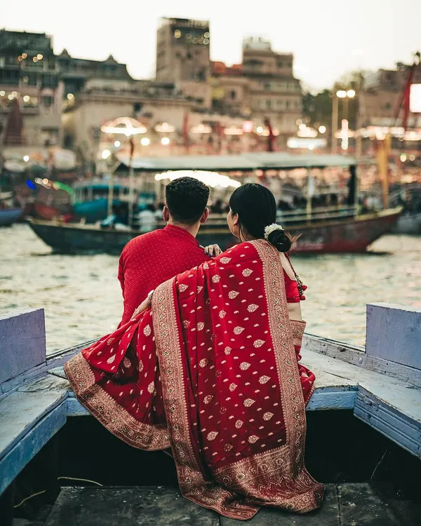 A wide shot from our Varanasi pre-wedding session, capturing the couple as they soak in the view of the ghats from their boat. The image establishes a sense of place, showing their shared moment against the vast, historic cityscape.