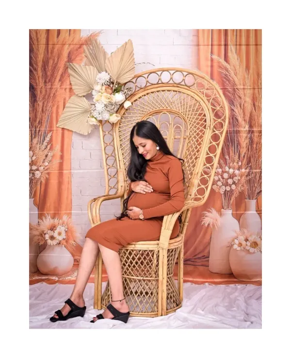 A serene solo portrait in our popular Boho setup. The large wicker peacock chair acts as a beautiful throne for the mom-to-be, and the earthy tones of her dress and the backdrop create a warm, natural feel.