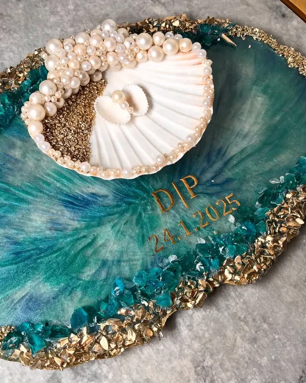 This is one of my absolute favorite creations, a unique ocean-inspired ring platter for a client from Assam. The design features a real seashell for the rings, set against a backdrop of swirling teal resin, sparkling crystals, and gold accents. I love collaborating on one-of-a-kind pieces like this.