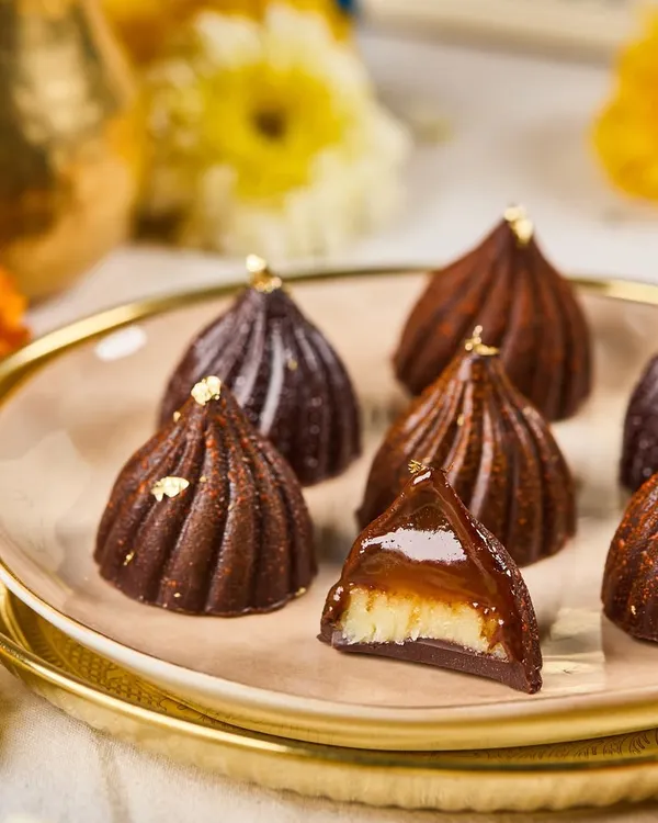 A close-up of our signature Modak Bonbons from the Ganpati menu. This one is filled with coconut-jaggery, capturing the traditional flavor in a modern chocolate shell.