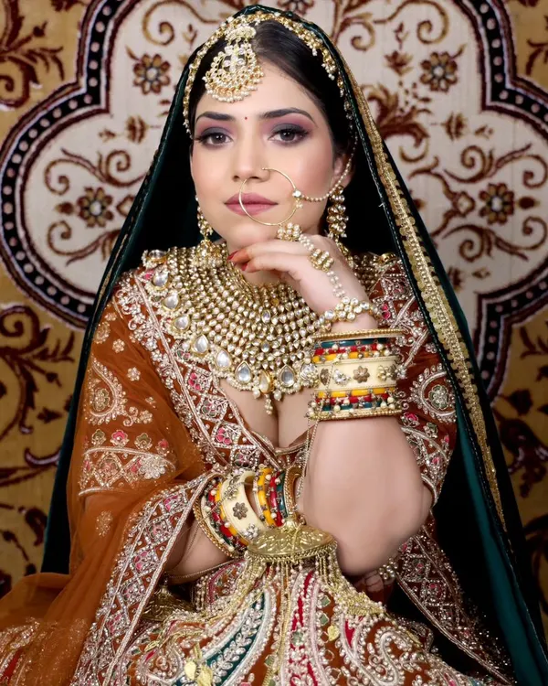 A truly regal look featuring a heavy, multi-layered Polki necklace paired with a wide choker, oversized jhumkas, a statement matha patti, and a delicate nath. This is for the bride who wants to make a grand entrance.