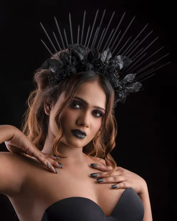 A powerful portrait for a gothic-themed shoot. The makeup is defined by a black smoky eye, bold black lipstick, and a dramatic black crown, creating a striking 'dark queen' character.