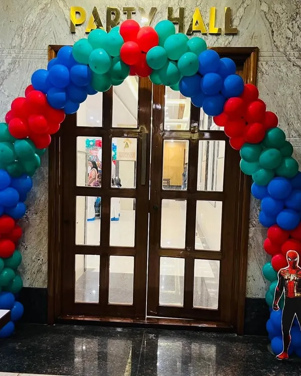 A classic balloon arch in superhero colors for the entrance to an Avengers-themed party hall.