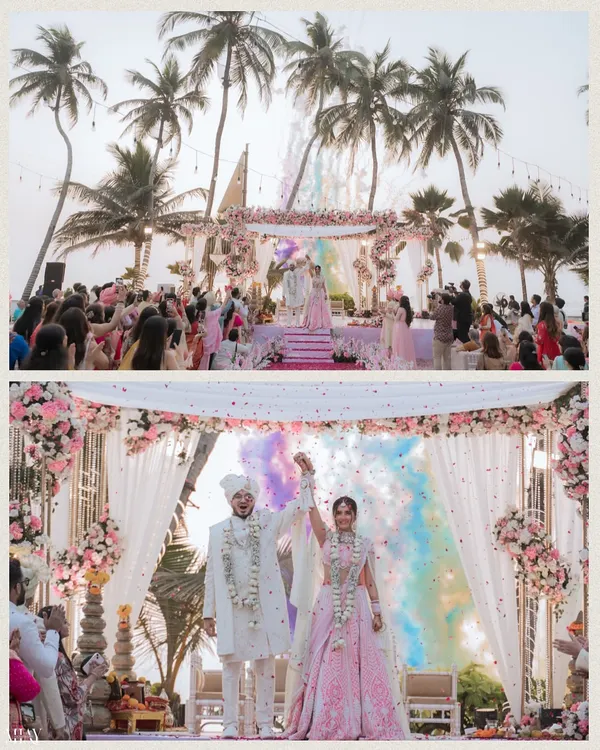 A stunning beachside Hindu wedding ceremony, capturing the Varmala moment with colorful smoke in the background.