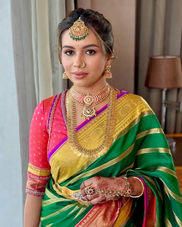 A close-up portrait capturing a flawless, radiant complexion paired with soft, defined eyes and a neutral lip. This look perfectly complements the client's magnificent temple jewellery and traditional Kanjivaram saree, embodying the essence of South Indian bridal elegance.