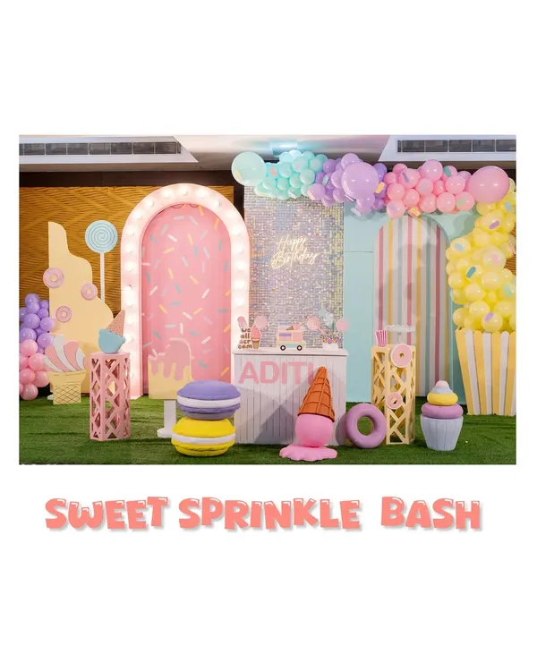 Welcome to the 'Sweet Sprinkle Bash'. This wide view shows our Candyland theme, complete with a donut-sprinkled arch, giant macarons, and ice cream props, all in a delightful pastel palette.
