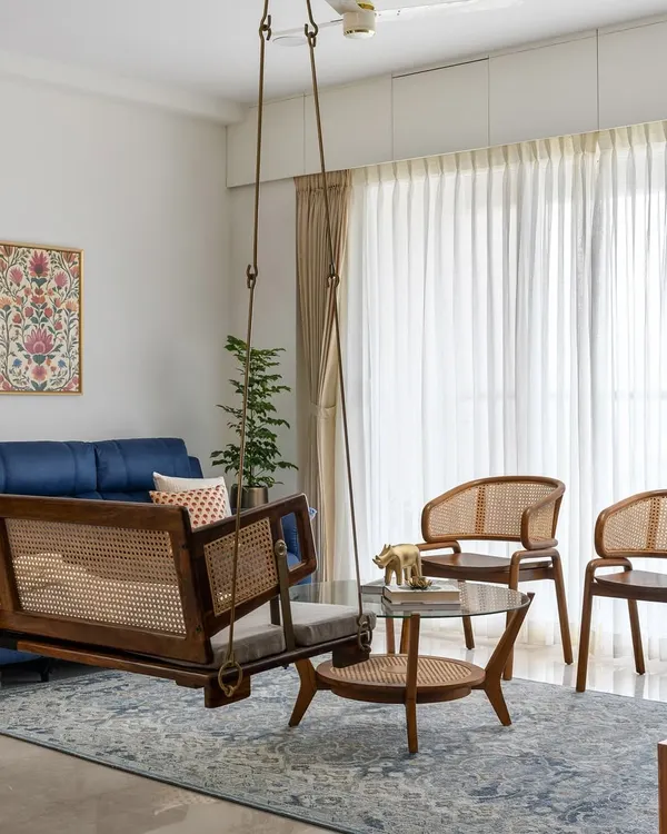 The living room in our 'Malhar' project is designed for connection, featuring a beautiful wood and cane swing that adds a playful, traditional touch. Paired with contemporary seating, it creates a balanced and inviting atmosphere for family and friends.