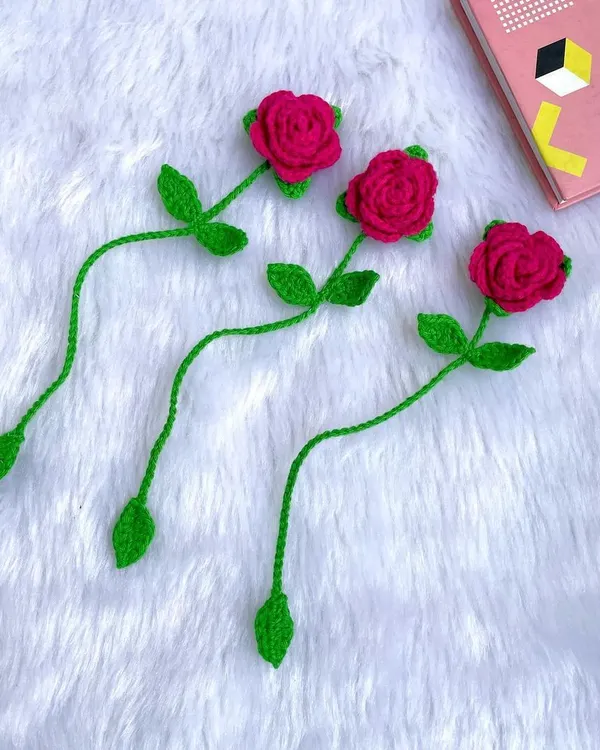 A set of three delicate red rose bookmarks. The long green stem tucks into the book, leaving the beautiful rose peeking out from the top.