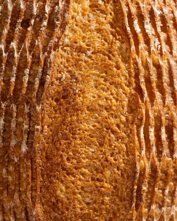 An extreme close-up of a sourdough crust. This macro shot is all about texture, highlighting the beautiful, crunchy surface of the bread.
