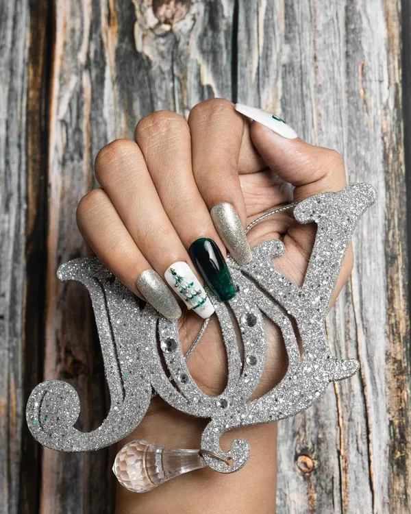 Get into the festive spirit with this Christmas nail set. It features a mix of green chrome, silver glitter, and a hand-painted Christmas tree for a joyful holiday look.