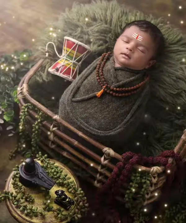 A powerful and serene portrait of a newborn as little Mahadev. This overhead shot captures the full divine setup, including the Shivling, Trishul, and Rudraksha beads.