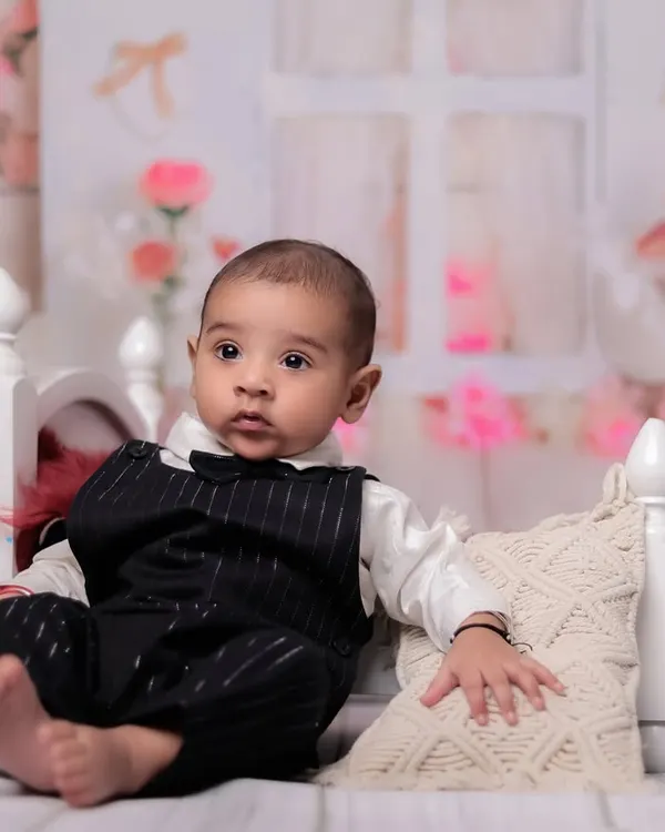 A classic portrait of a 4-month-old baby boy sitting up on the prop bed. His alert expression and formal outfit make for a very handsome photo.