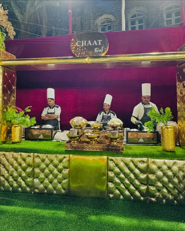 My grand, golden chaat counter, where chefs in traditional attire prepare a variety of Indian street food favorites.