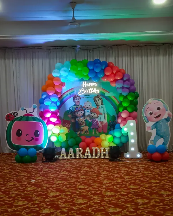 This Cocomelon themed stage is perfect for a first birthday party. The setup includes a full arch of rainbow balloons, large cutouts of the characters, a light-up number one, and a personalized backdrop to make the birthday child the star of the show.