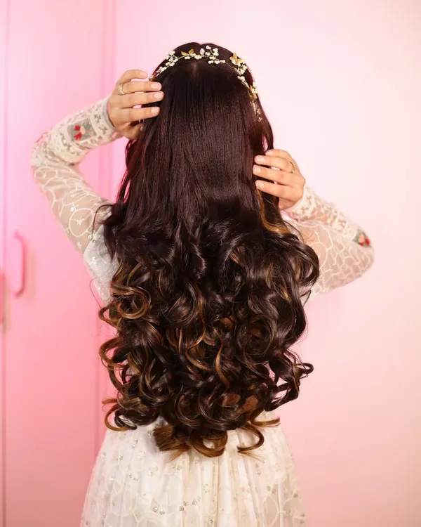 Hairstyle goals. This stunning open hairstyle features voluminous curls and a beautiful hair accessory, perfect for a reception or engagement.
