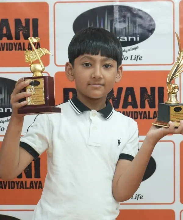 Double the joy! This young achiever proudly displays his two trophies from the Dhwani Kala Mahotsav, a result of his hard work in multiple disciplines.